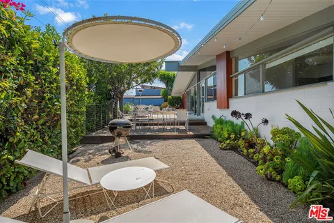 a view of a patio with table and chairs potted plants