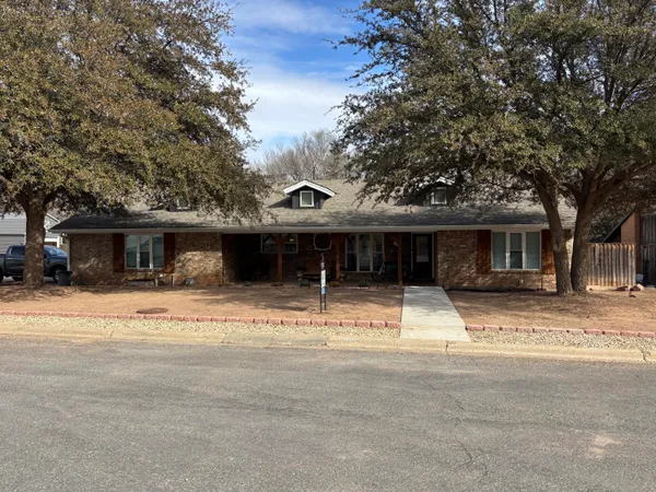 a view of a house with a yard and large tree