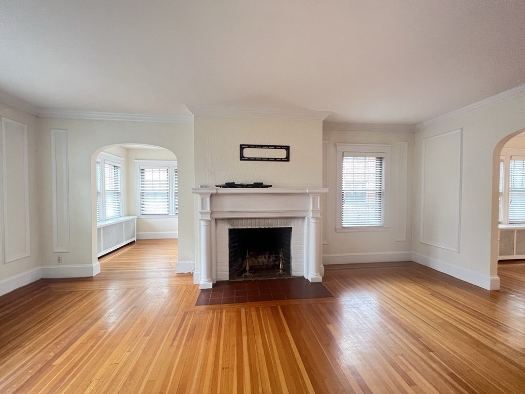 84 Winthrop Road Brookline, MA 02445 - Photo 4 of 42 an empty room with wooden floor fireplace and windows