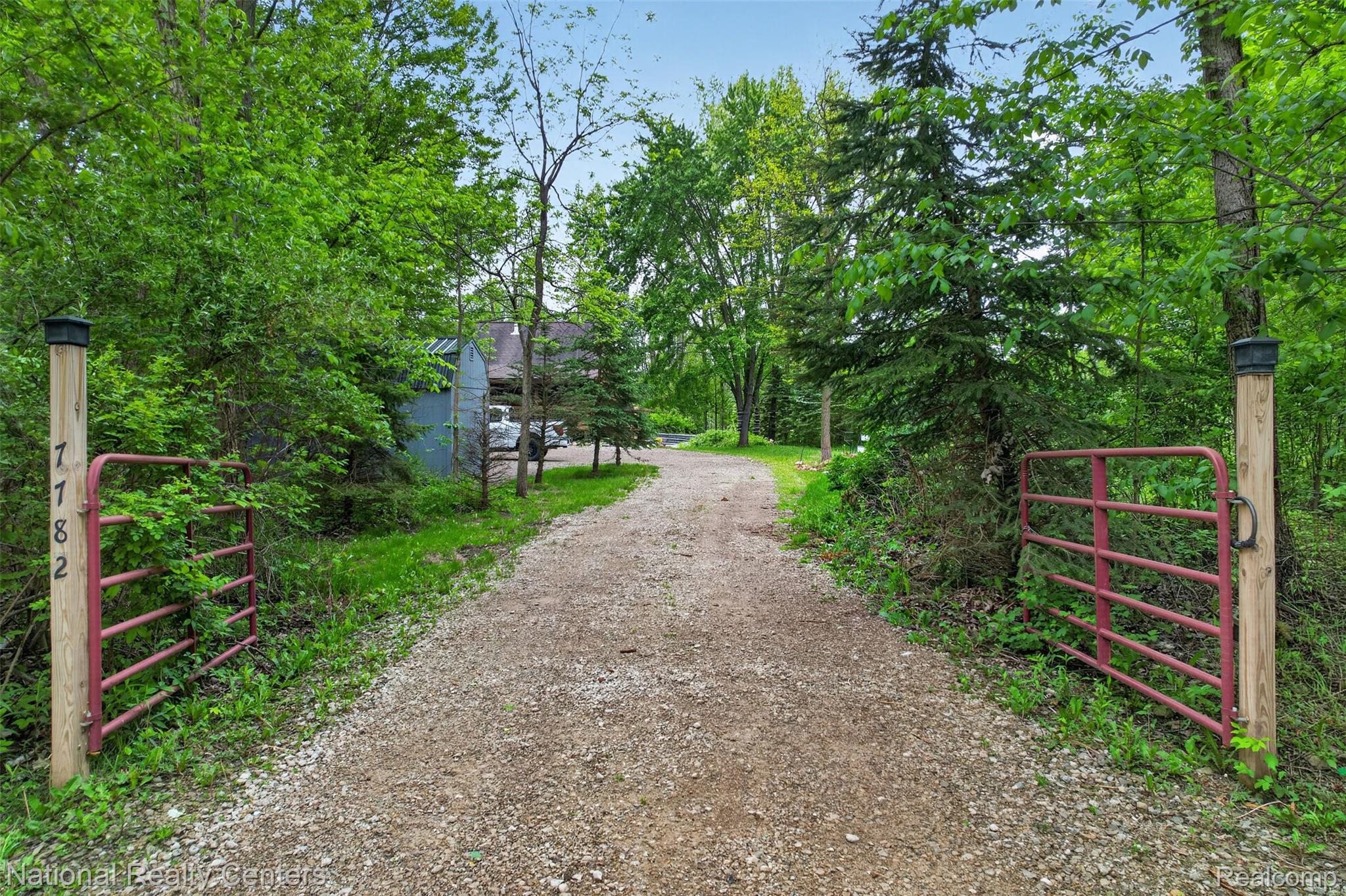 7782 Golf Club Road Howell, MI 48843 - Photo 25 of 27 Gated gravel driveway framed by mature trees and lush greenery