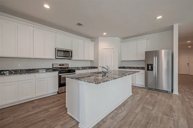 a kitchen with a sink stove a refrigerator and white cabinets