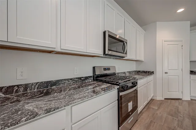 a kitchen with granite countertop white cabinets and stainless steel appliances