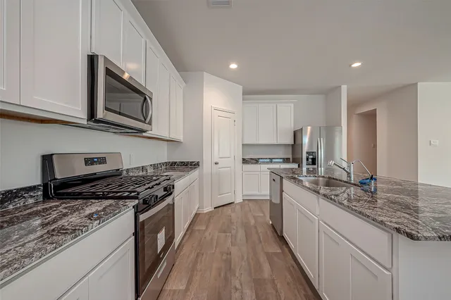 a kitchen with stainless steel appliances granite countertop a stove a sink and a microwave