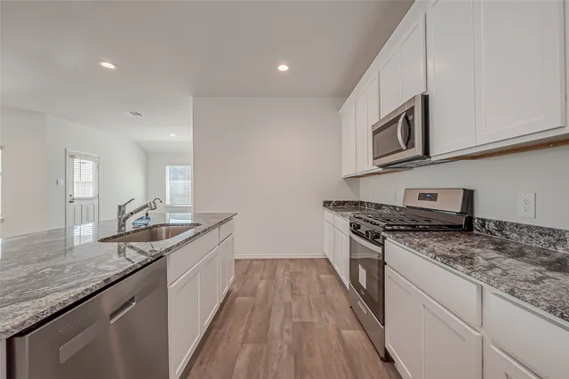 a kitchen with granite countertop stainless steel appliances window a sink and a counter space