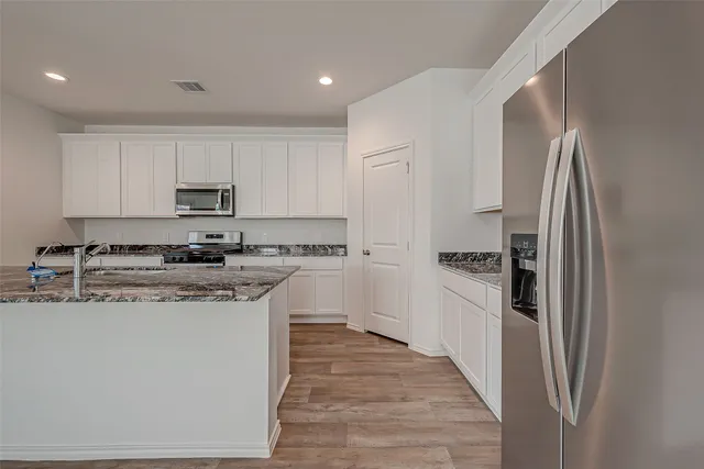 a kitchen with stainless steel appliances granite countertop a refrigerator a stove and a sink