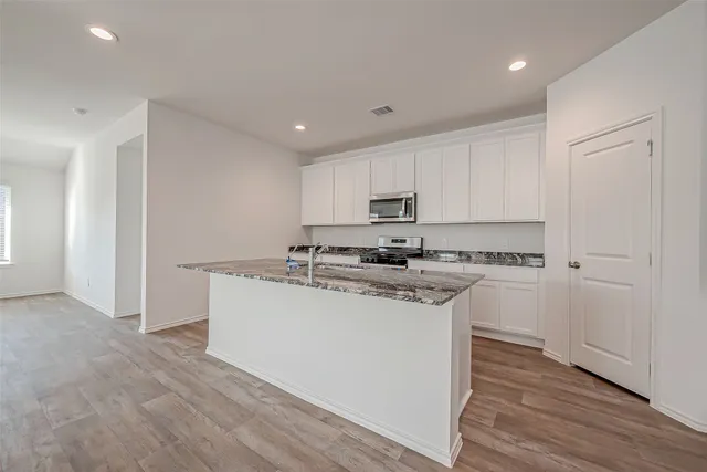 a kitchen with stainless steel appliances granite countertop a white stove top oven and white cabinets