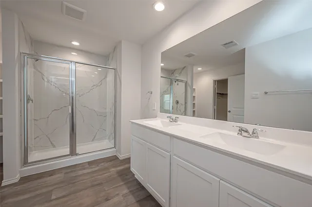 a bathroom with a double vanity sink mirror and shower