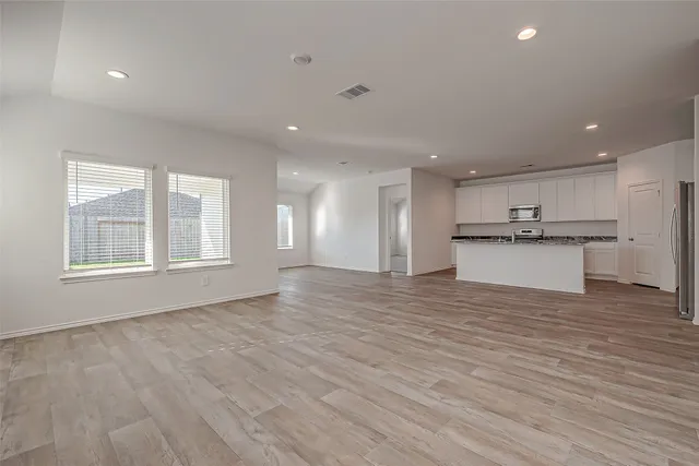a view of an empty room with a window and wooden floor