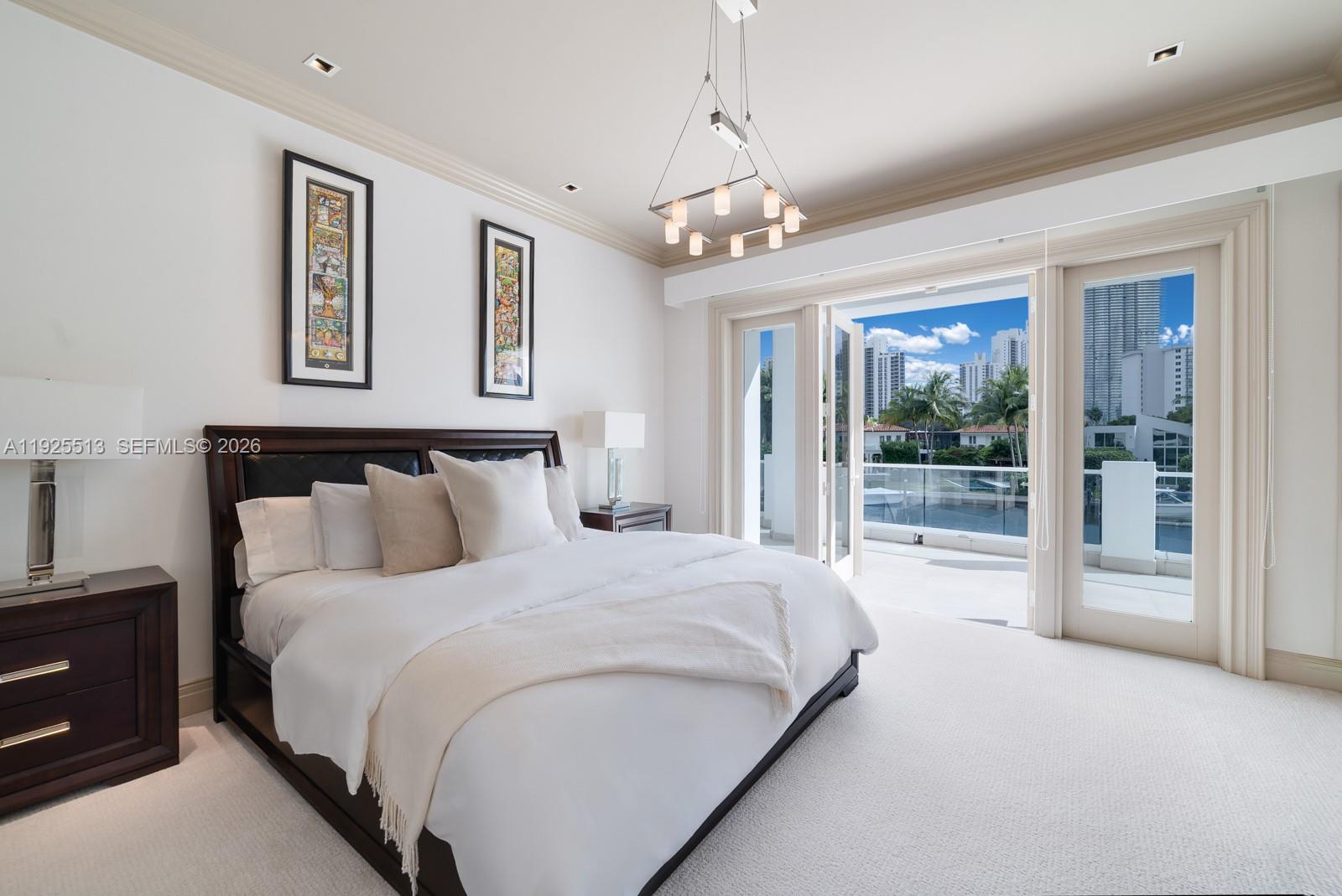 142 South Island Road Golden Beach, FL 33160 - Photo 22 of 55 a spacious bedroom with a large bed and a chandelier