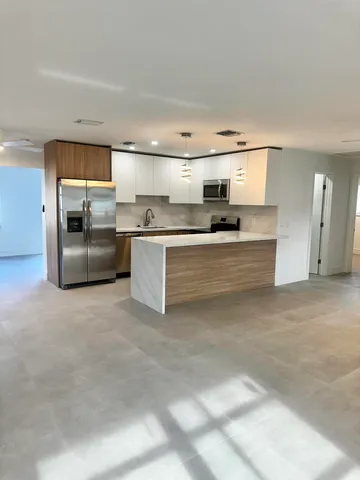 a large white kitchen with stainless steel appliances granite countertop a stove and a refrigerator