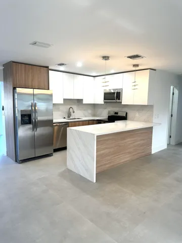 a kitchen with stainless steel appliances granite countertop a sink and a refrigerator