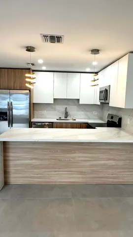 a view of kitchen with kitchen island a sink stainless steel appliances and cabinets