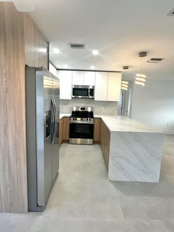 a large kitchen with a refrigerator a stove and a sink