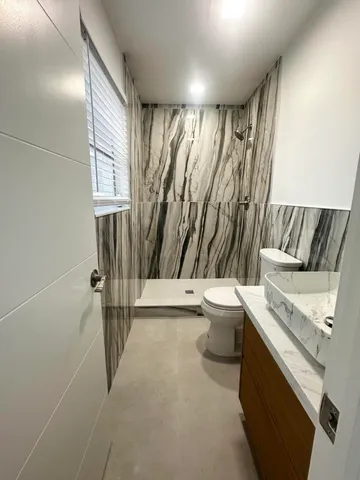 a bathroom with a granite countertop sink toilet and shower
