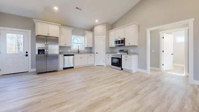 a view of a hallway with wooden floor and a bathroom