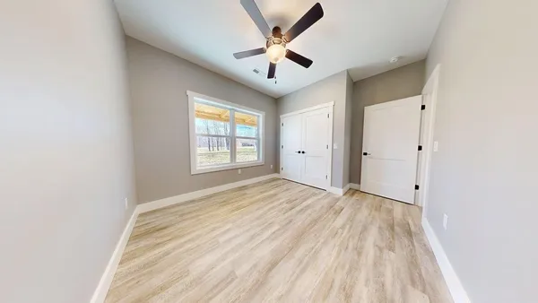 an empty room with windows and a ceiling fan