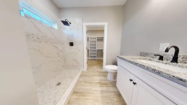a spacious bathroom with a granite countertop sink a toilet and shower