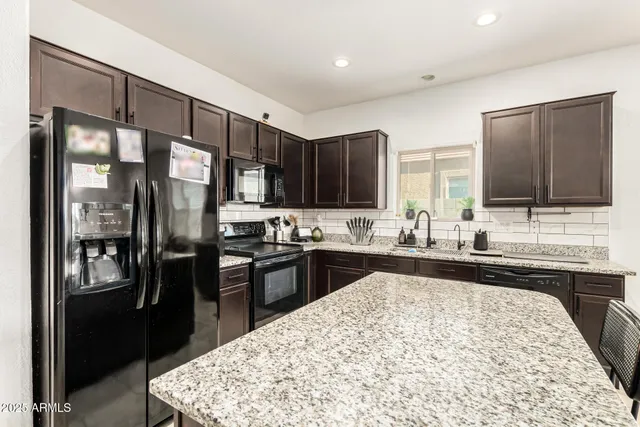 a kitchen with stainless steel appliances kitchen island granite countertop a refrigerator stove top oven and sink
