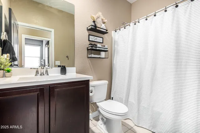 a bathroom with a sink a toilet a mirror and shower curtain