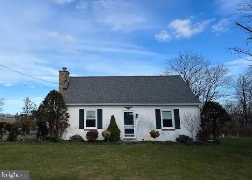 a front view of house with yard and trees in the background