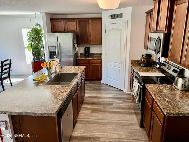 a kitchen with granite countertop a refrigerator a stove and a sink