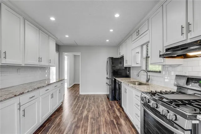 a kitchen with stainless steel appliances a stove top oven a sink a refrigerator and cabinets