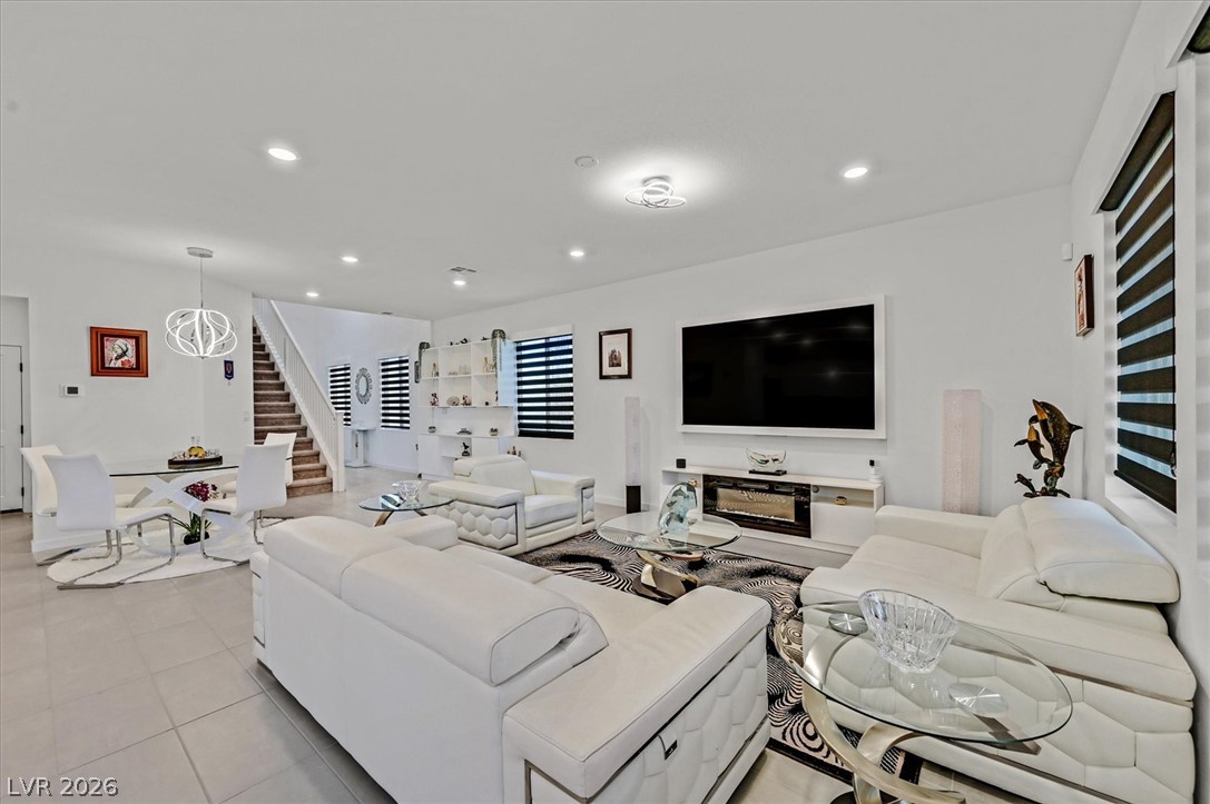 2933 Little Current Road North Las Vegas, NV 89086 - Photo 6 of 35 Discover a naturally illuminated living area featuring sleek tile flooring and a sophisticated dining space adjacent to a grand staircase.