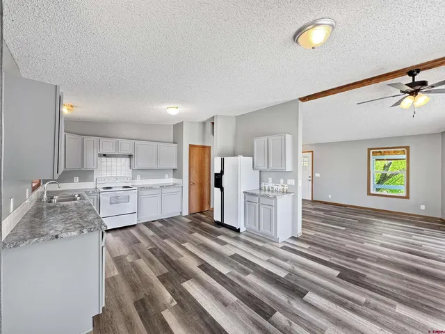 a large white room with kitchen island a white cabinets and wooden floor