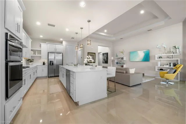 a kitchen with stainless steel appliances kitchen island a table chairs sink and cabinets