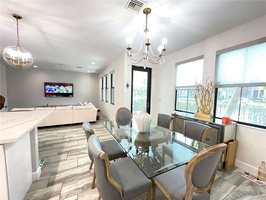 Undisclosed Address Sunrise, FL 33323 - Photo 20 of 88 a living room with couches chandelier and a dining table with wooden floor