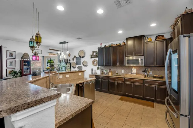 a large kitchen with stainless steel appliances granite countertop a sink and a refrigerator