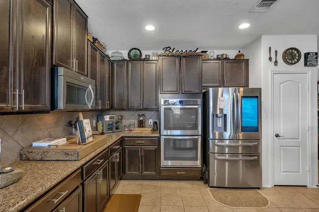 a kitchen with granite countertop stainless steel appliances a refrigerator a sink a stove and cabinets
