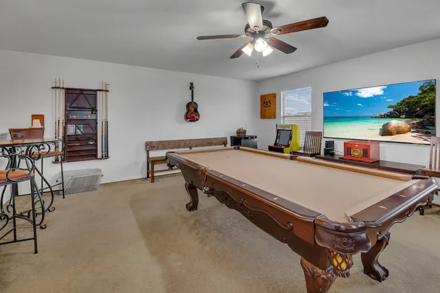 a living room with pool table and a ceiling fan