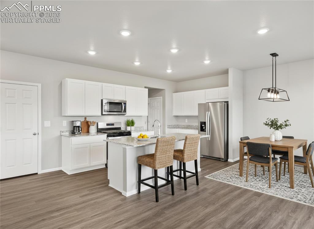 6754 Roundtail Way Colorado Springs, CO 80925 - Photo 2 of 31 a kitchen with stainless steel appliances a dining table chairs and granite counter tops