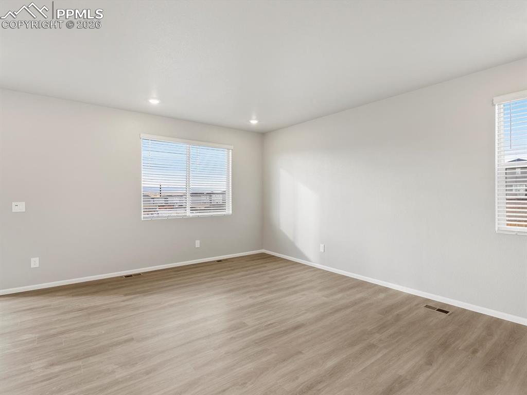 6754 Roundtail Way Colorado Springs, CO 80925 - Photo 5 of 31 an empty room with wooden floor and windows