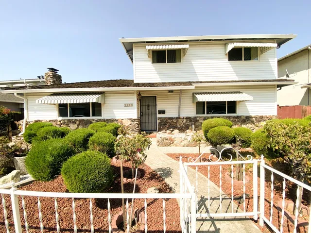 a front view of a house with glass windows and plants