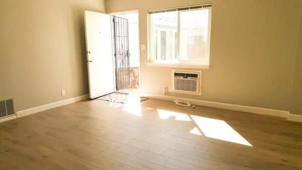 a view of an empty room with wooden floor and a bathroom