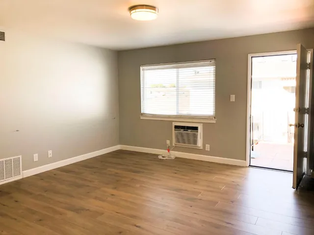 an empty room with wooden floor and windows