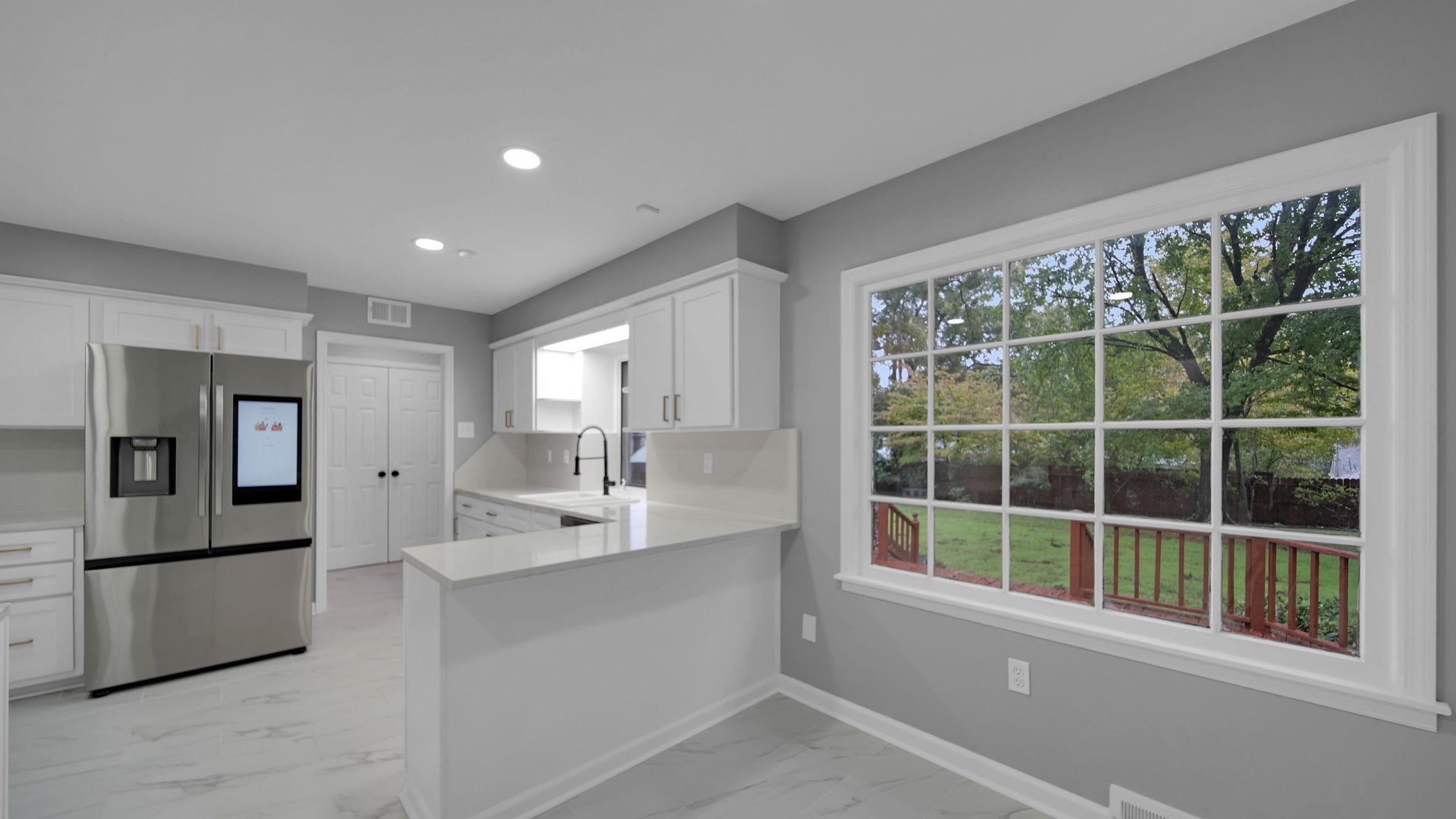 5256 Collingwood Road Memphis, TN 38117 - Photo 16 of 40 Kitchen featuring stainless steel fridge, white cabinetry, light marble finish flooring, a peninsula, and recessed lighting