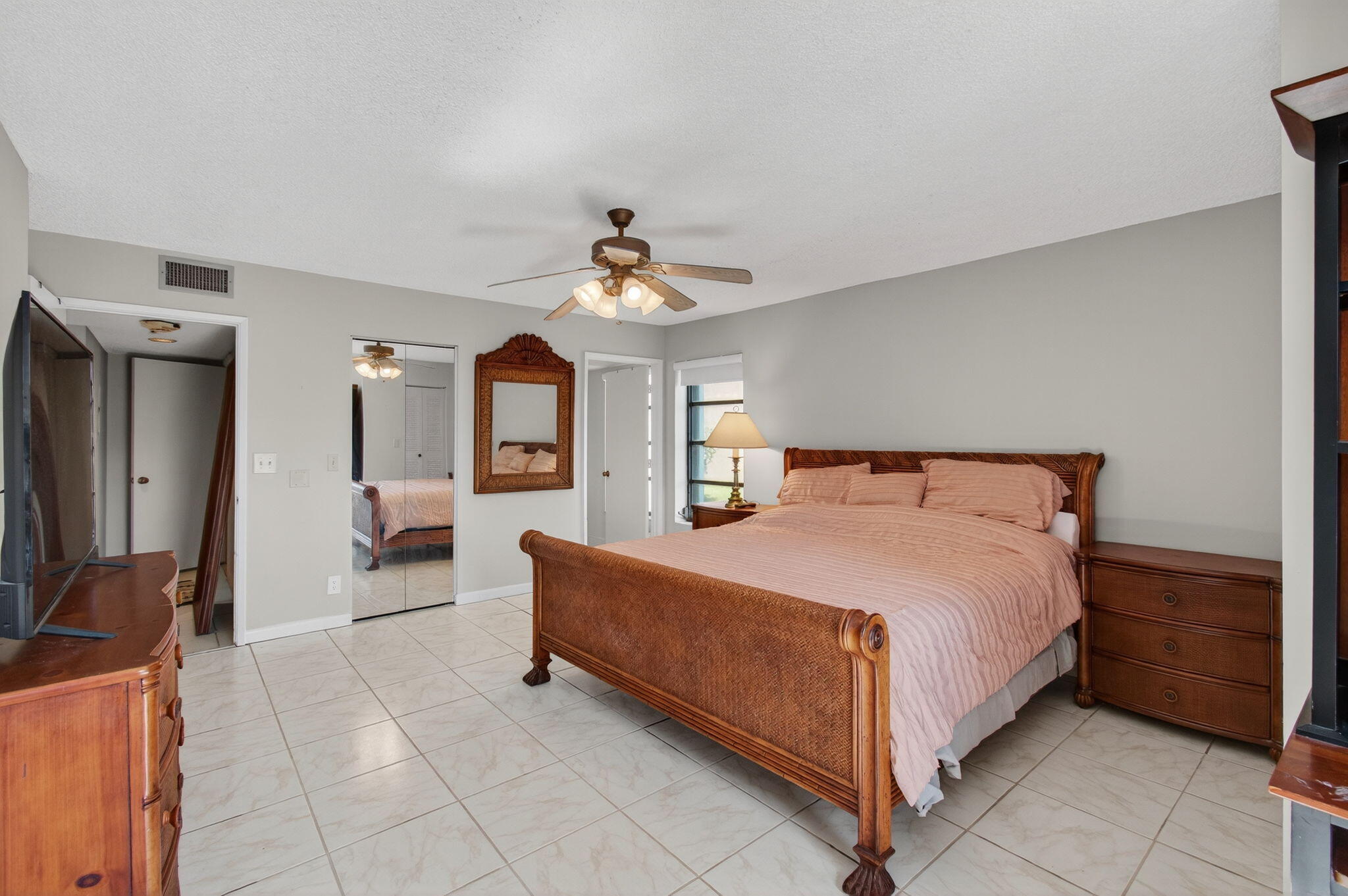 7340 Amberly Lane, Unit 101 Delray Beach, FL 33446 - Photo 35 of 90 a spacious bedroom with a bed a chandelier and dresser