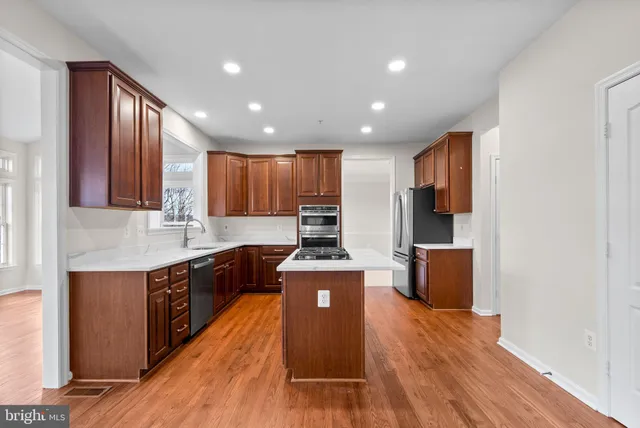 a kitchen with stainless steel appliances granite countertop a stove a refrigerator and a stove with wooden floors