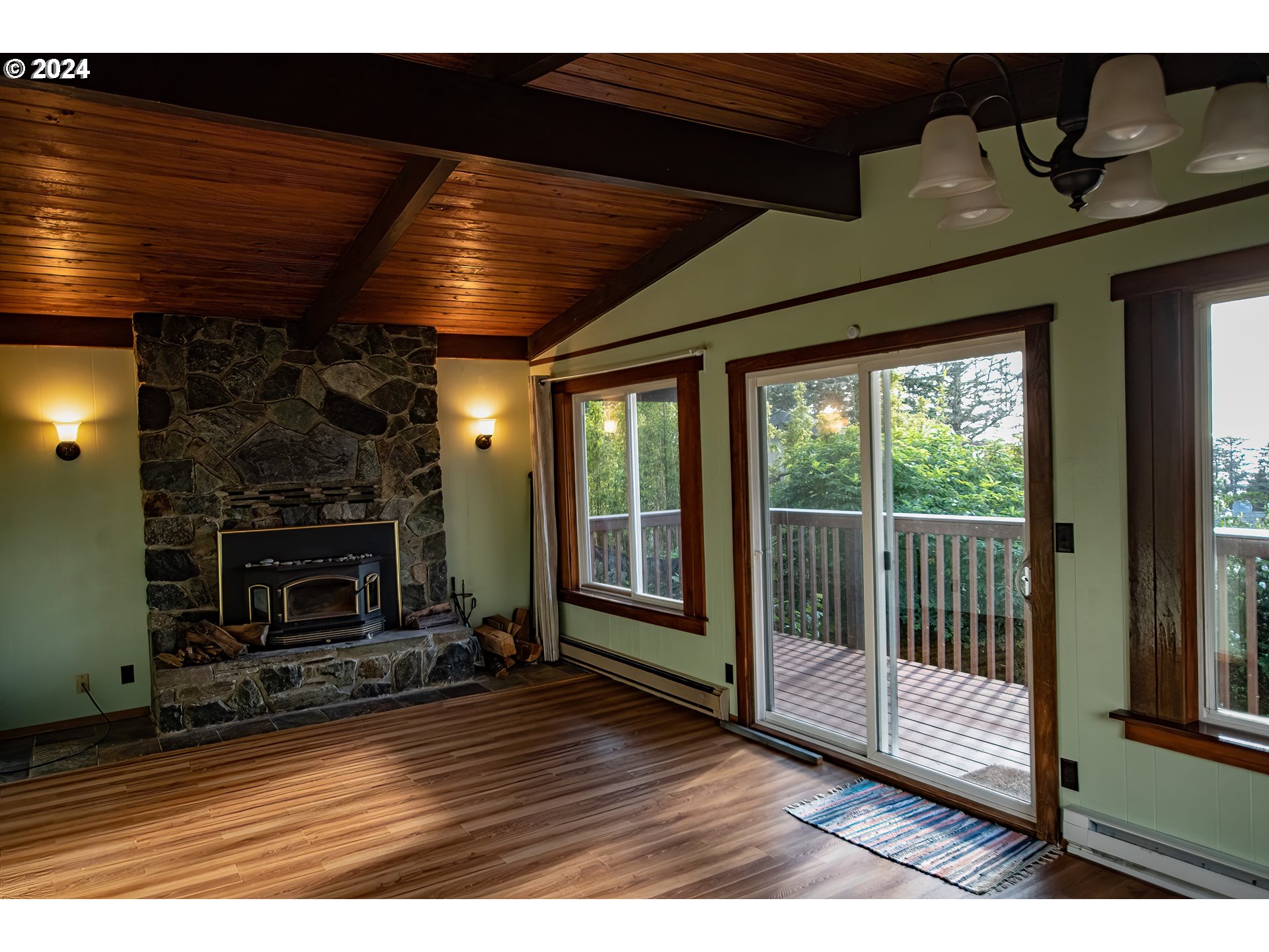 29280 Lacy Street Gold Beach, OR 97444 - Photo 5 of 38 a view of an empty room with wooden floor fireplace and a window
