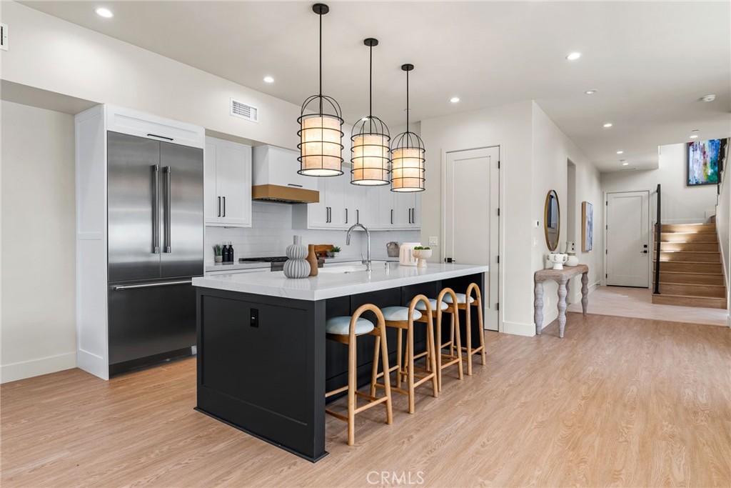 161 Cecil Place, Unit A Costa Mesa, CA 92627 - Photo 15 of 63 a kitchen with stainless steel appliances granite countertop a refrigerator a sink dishwasher a oven and a dining table with wooden floor