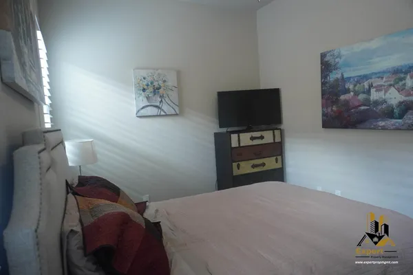 a bedroom with a bed and a lamp on dresser