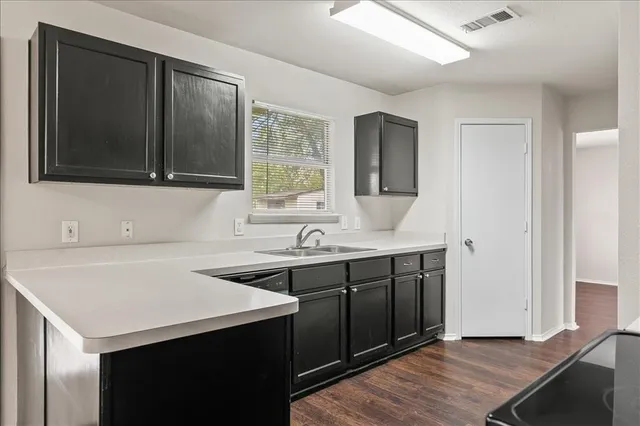 a kitchen with a sink cabinets and wooden floor