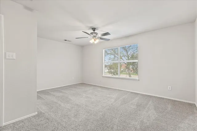 an empty room with windows and fan