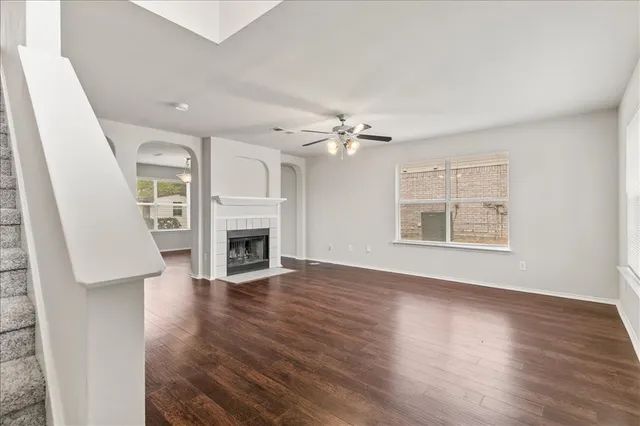 a view of an empty room with wooden floor fireplace and a window