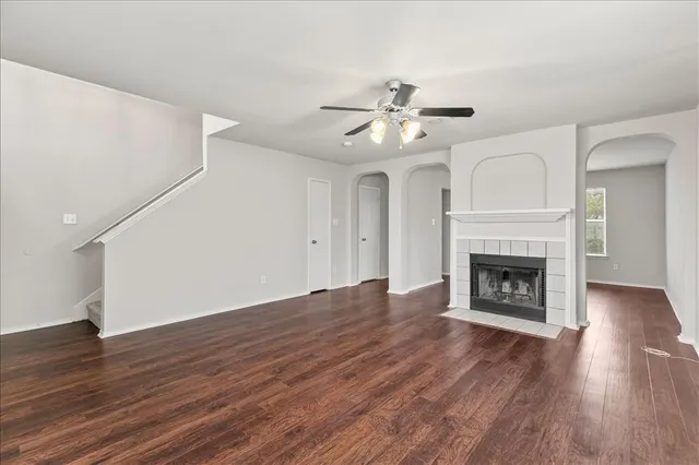 a view of an empty room with wooden floor fireplace and a window