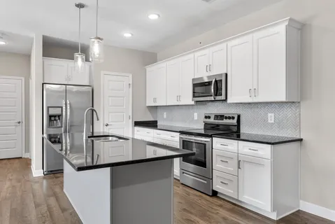 a kitchen with stainless steel appliances granite countertop a stove top oven a refrigerator and white cabinets