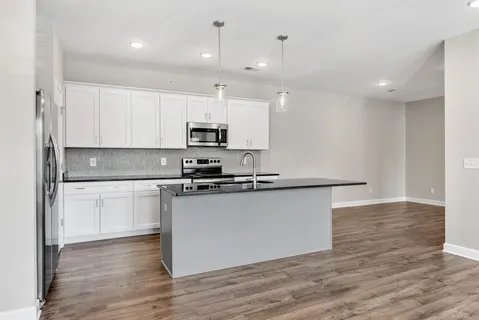 a kitchen with stainless steel appliances a microwave a sink cabinets and wooden floor